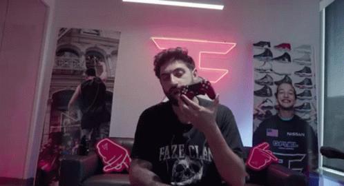 A Man Is Sitting On A Couch Holding A Video Game Controller In His Hand . GIF