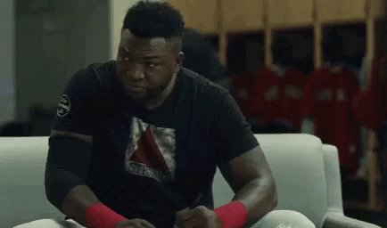 a man is sitting on a couch in a locker room wearing a black shirt .