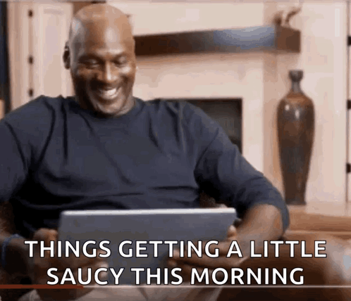 A Man Is Sitting On A Couch Looking At A Tablet With The Words Things Getting A Little Saucy This Morning GIF