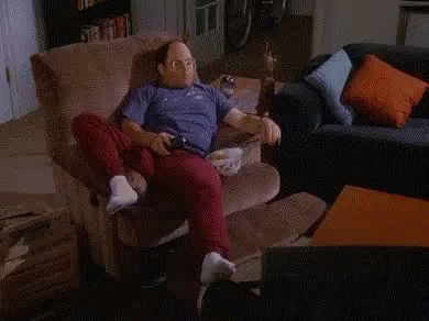 A Man Is Sitting On A Couch Next To A Shelf Full Of Sodas And Snacks GIF