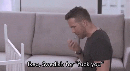 a man is sitting on a couch smoking a cigarette and talking on his phone .