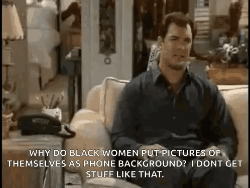 A Man Is Sitting On A Couch Talking To A Woman While Holding A Telephone . GIF