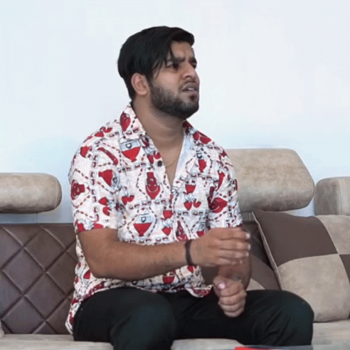 A Man Is Sitting On A Couch Wearing A Shirt That Says ' A ' On It GIF