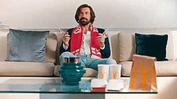 A Man Is Sitting On A Couch With A Mcdonald 'S Bag In Front Of Him . GIF
