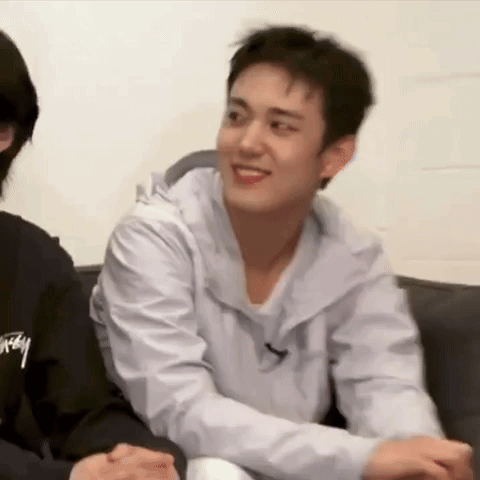 A Man Is Sitting On A Couch With His Arms Around Another Man . GIF