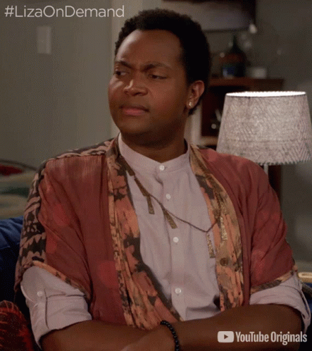 A Man Is Sitting On A Couch With His Arms Crossed And A Youtube Originals Advertisement Behind Him GIF