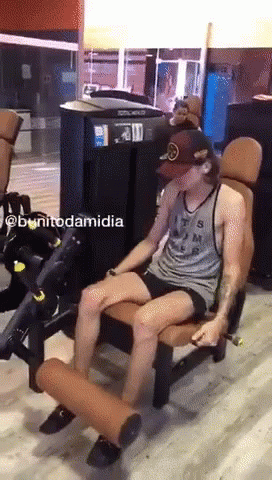 A Man Is Sitting On A Machine In A Gym With The Name Bonitodamidia Written On The Bottom GIF