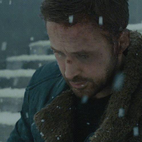 A Man Is Sitting On A Set Of Stairs In The Snow Looking At His Phone GIF