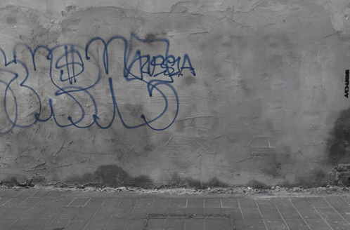 A Man Is Sitting On A Skateboard On A Wall With Graffiti On It That Says Destroy GIF