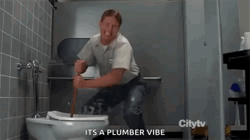 A Man Is Sitting On A Toilet With A Plunger In His Hand In A Bathroom . GIF