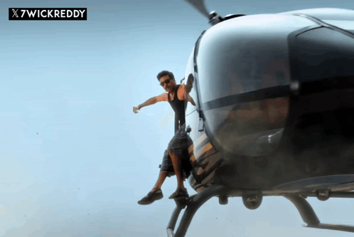 A Man Is Sitting On The Back Of A Helicopter With X7wickreddy Written On The Bottom GIF