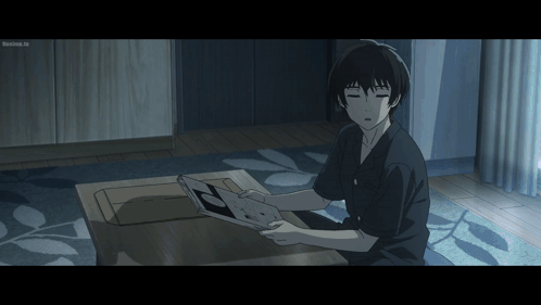 A Man Is Sitting On The Floor Looking At A Book And The Screen Says ' Tokyo Ghoul ' On The Bottom GIF