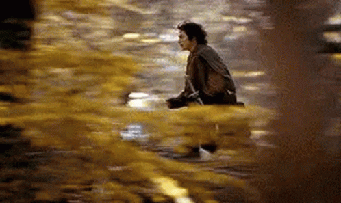 A Man Is Sitting On The Ground In A Puddle Of Water . GIF