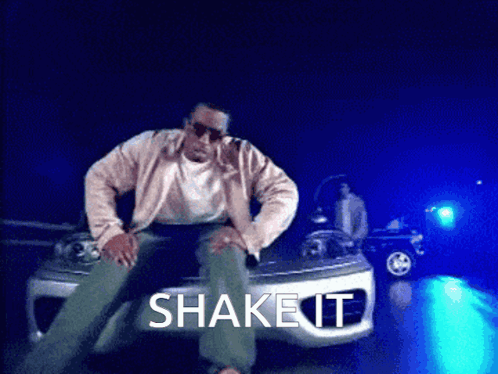 A Man Is Sitting On The Hood Of A Car With The Words Shake It Written Above Him GIF
