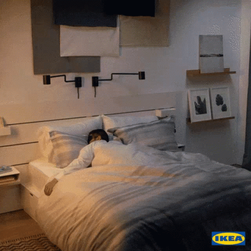 A Man Is Sleeping In A Bed With An Ikea Logo In The Background GIF