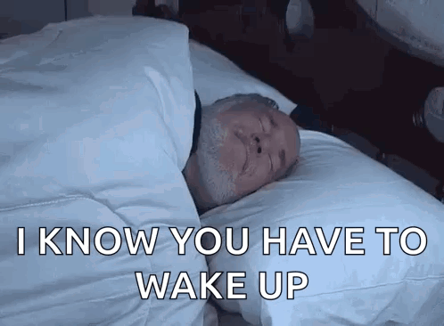 A Man Is Sleeping In A Bed With The Words `` I Know You Have To Wake Up '' Written On The Bottom . GIF
