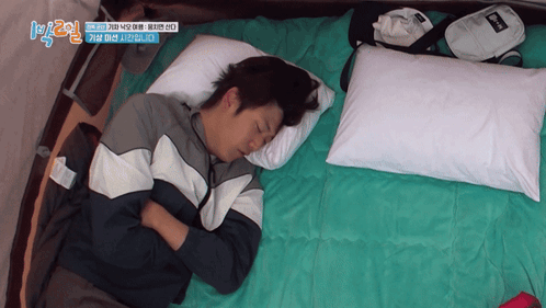 A Man Is Sleeping On A Bed With A Bag That Says ' Reebok ' On It GIF