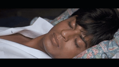 A Man Is Sleeping With His Eyes Closed And His Shirt Off GIF