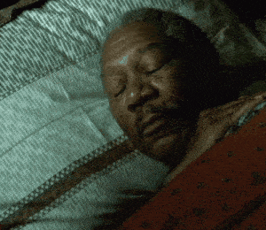 A Man Is Sleeping With His Eyes Closed In A Dark Room GIF