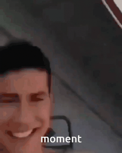 A Man Is Smiling And Holding A Yellow Object In Front Of Him With The Word Moment Visible GIF
