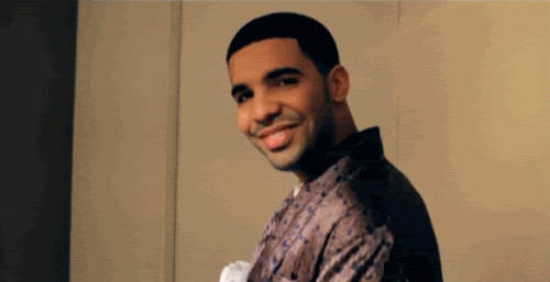 A Man Is Smiling And Looking At The Camera While Wearing A Robe . GIF