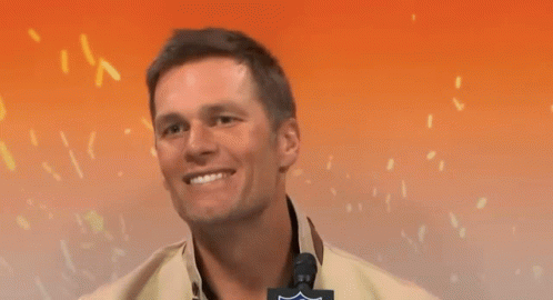 A Man Is Smiling And Pointing At The Camera With A Nfl Logo On His Jacket GIF