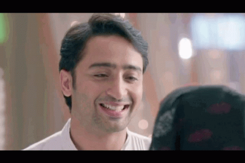 A Man Is Smiling At A Woman In A Black Hijab . GIF