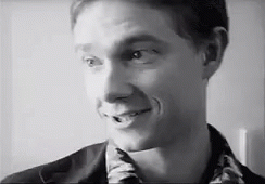 A Man Is Smiling In A Black And White Photo . GIF