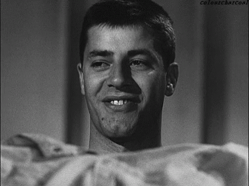 A Man Is Smiling In A Black And White Photo With Colonycharcoal Written Below Him GIF