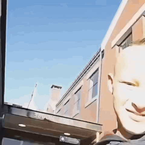 A Man Is Smiling In Front Of A Building That Has The Number 36 On The Side GIF