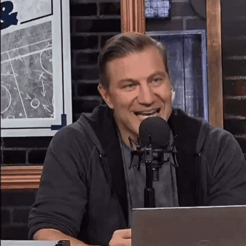 A Man Is Smiling In Front Of A Microphone While Sitting In Front Of A Dell Laptop GIF