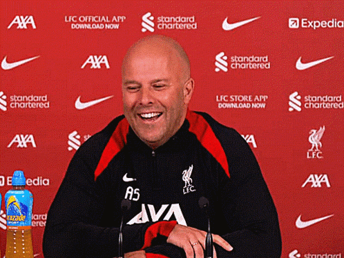 A Man Is Smiling In Front Of A Red Background That Says ' Standard Chartered ' GIF