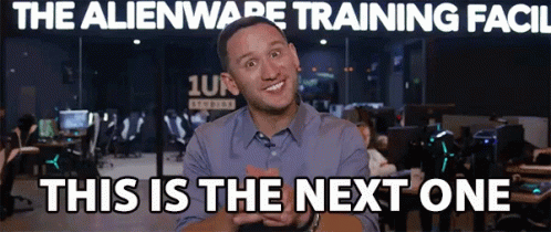 A Man Is Smiling In Front Of A Sign That Says " The Alienware Training Facil " GIF