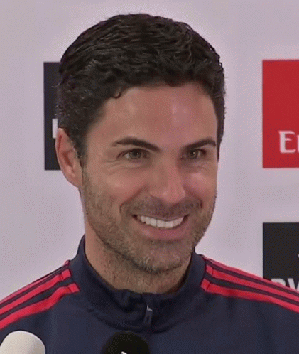 A Man Is Smiling In Front Of An Emirates Logo GIF