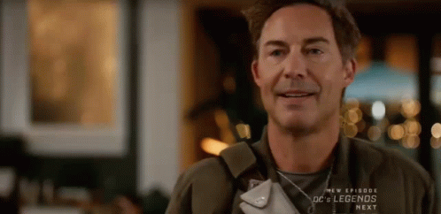 A Man Is Smiling While Holding A Purse In His Hand . GIF