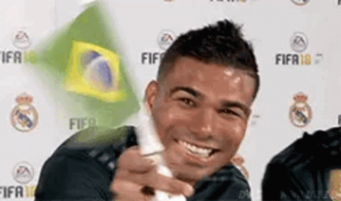 a man is smiling while holding a wii controller in front of a brazilian flag .