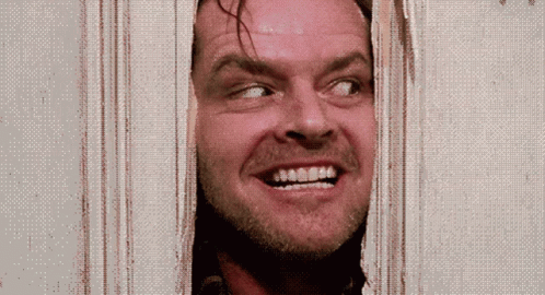 A Man Is Smiling While Looking Through A Door GIF