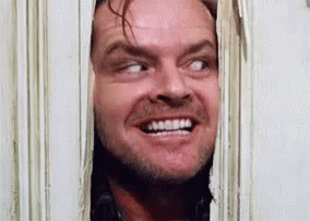A Man Is Smiling While Looking Through A Doorway . GIF