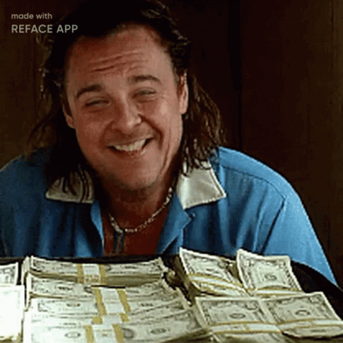 A Man Is Smiling While Sitting In Front Of A Pile Of Money Made By Reface App GIF