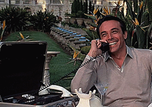 A Man Is Smiling While Talking On A Cell Phone GIF