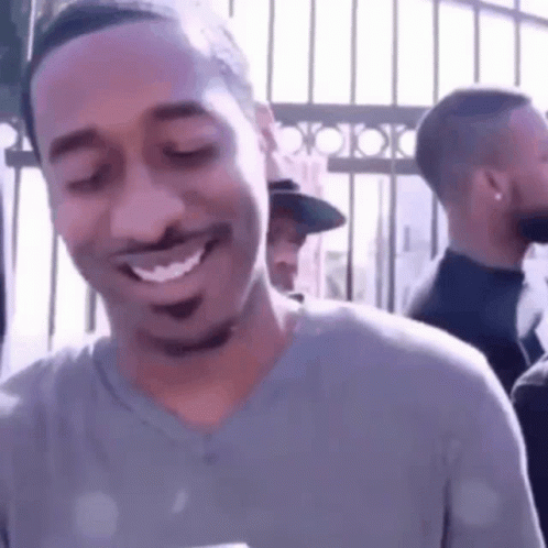 A Man Is Smiling With His Eyes Closed While Standing In Front Of A Crowd . GIF