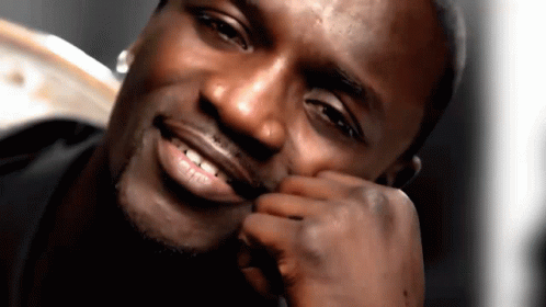 A Man Is Smiling With His Hand On His Face GIF