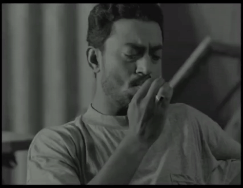 A Man Is Smoking A Cigarette In A Black And White Photo GIF