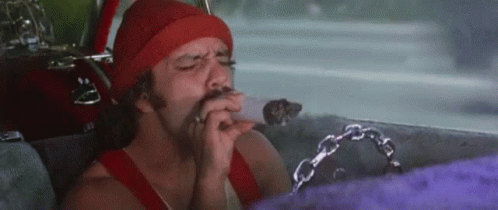 A Man Is Smoking A Cigarette In A Car While Wearing A Red Hat . GIF