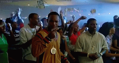 A Man Is Smoking A Cigarette In A Crowd Of People At A Party . GIF