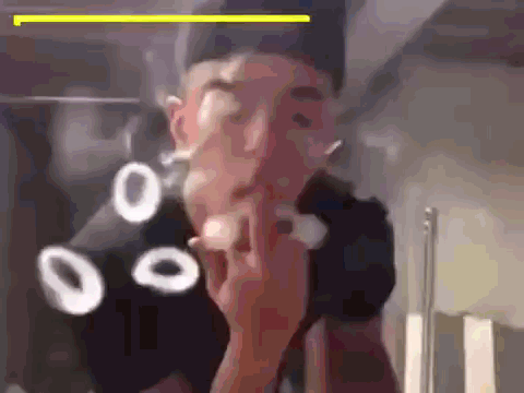 A Man Is Smoking A Cigarette In Front Of A Mirror While Wearing A Black Hat . GIF
