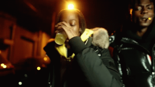 A Man Is Smoking A Cigarette While A Woman Drinks From A Bottle . GIF