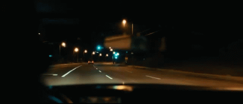 A Man Is Smoking A Cigarette While Driving A Car At Night . GIF