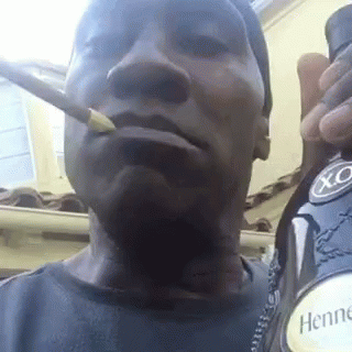 A Man Is Smoking A Cigarette While Holding A Bottle Of Hennessy X.o. GIF