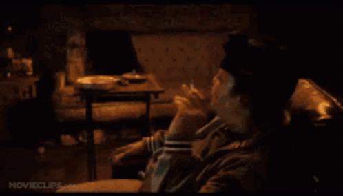 A Man Is Smoking A Cigarette While Sitting On A Couch . GIF